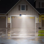 Solar motion sensor wall light illuminating a garage entrance